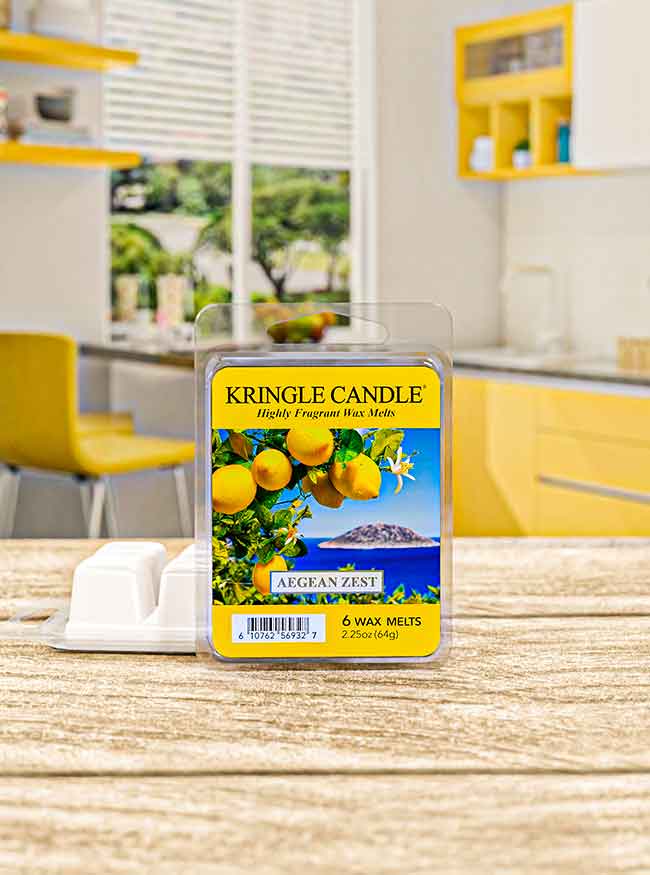 A pack of Aegean Zest Kringle Candle wax melts with lemon imagery, on a wooden table in a bright, modern kitchen.