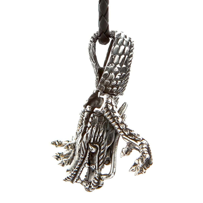 Hanging oxidized silver dragon pendant on a braided leather cord, looking down the back to reveal textured skull ridges.