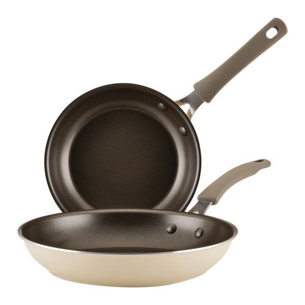 The 2-Piece Cook + Create Nonstick Frying Pan Set includes two stacked frying pans with sleek black interiors and elegant beige aluminum exteriors.