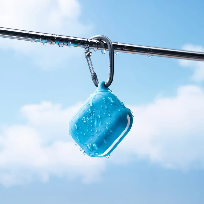 The Catalyst Case US AirPods (Gen 3) Waterproof Case + Carabiner is a rugged, blue, square-shaped case hanging from a metal rail under bright skiesÃƒÂ¢Ã¢â€šÂ¬Ã¢â‚¬Âideal for outdoor use and built to protect your AirPods against the elements.