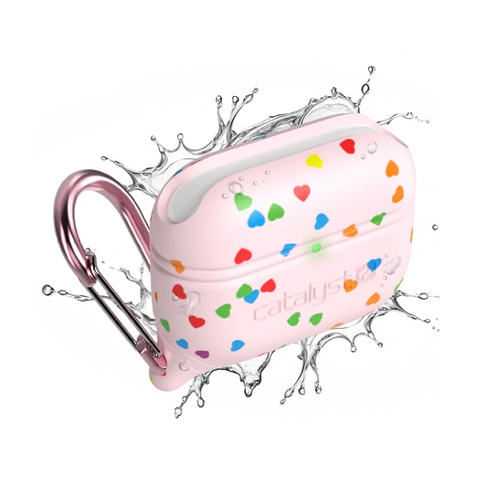 A Catalyst Case US AirPods Pro (Gen 3/2/1) Waterproof Case with a pink rainbow heart design and metallic pink carabiner is shown with splashing water, highlighting its rugged, water-resistant build against a white background.