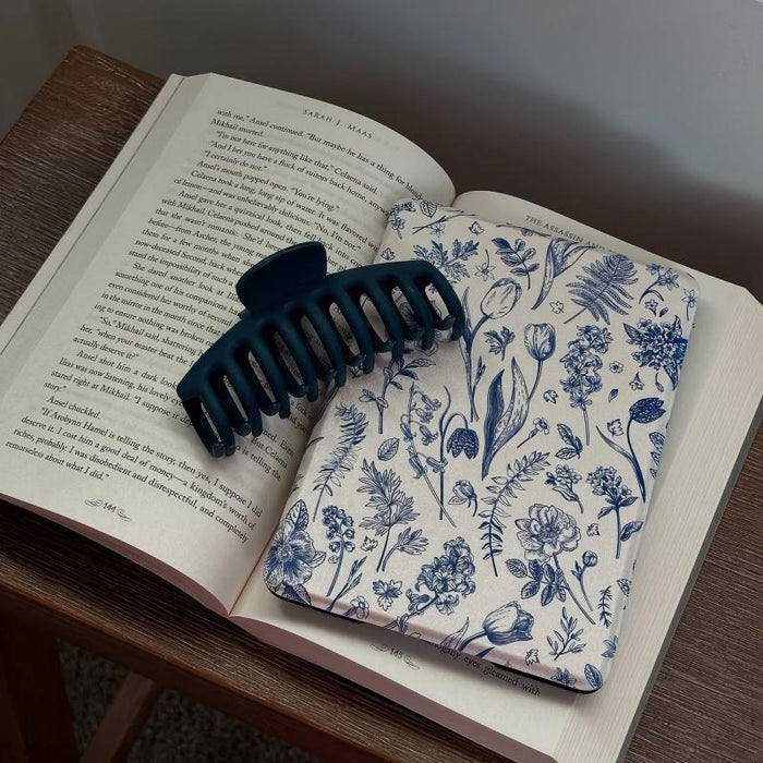 Two dark blue hair clips on an open book with floral pattern