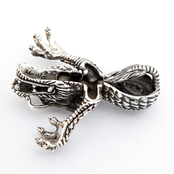Underside detail of the silver dragon pendant, highlighting the hollow jaw structure, claws, and large scaled chain bail.