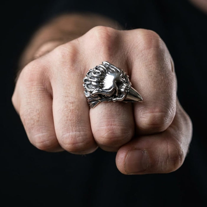 A close-up of a man's clenched fist wearing a heavy 925 sterling silver screaming eagle ring, featuring detailed feathers and a sharp beak in a bold biker style against a dark background.