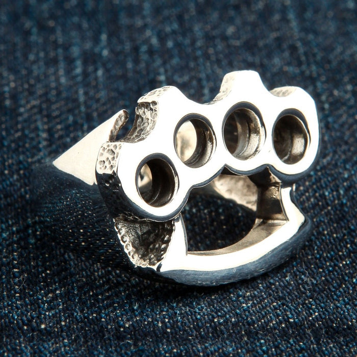 Angled view of 925 sterling silver brass knuckle style ring on denim background