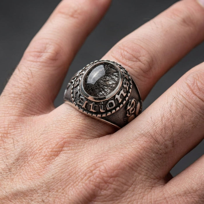 Black rutilated quartz Christian ring worn on man's hand showing cabochon stone and carved details