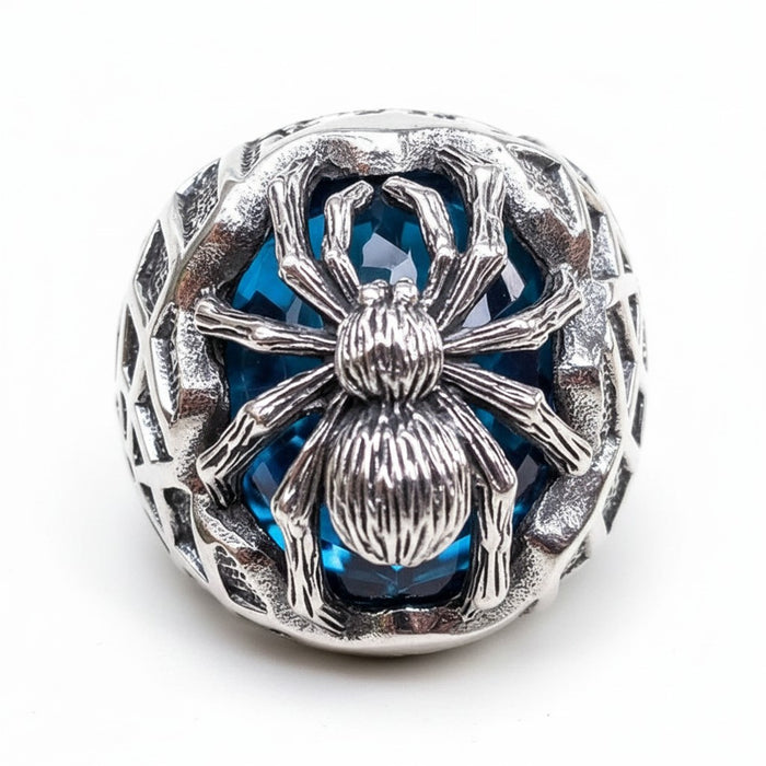 A studio shot of the handcrafted silver spider ring with its blue stone on a neutral background.