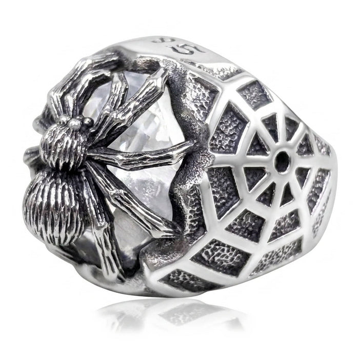 Sterling silver spider ring at three-quarter angle, oxidized web band wrapping a clear cubic zirconia stone