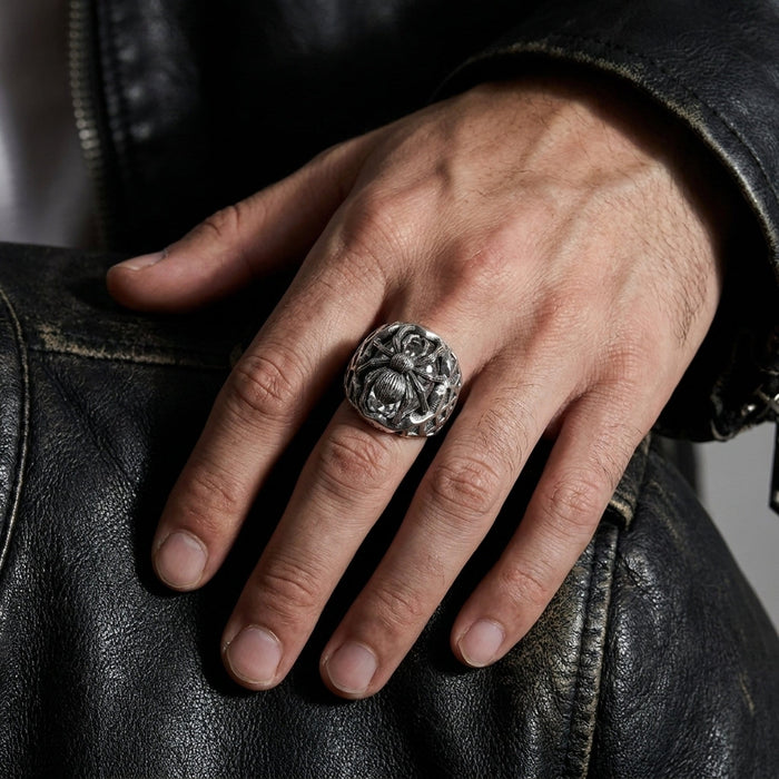 Worn on a man's hand against a black leather jacket, the silver spider ring shows its bold domed face