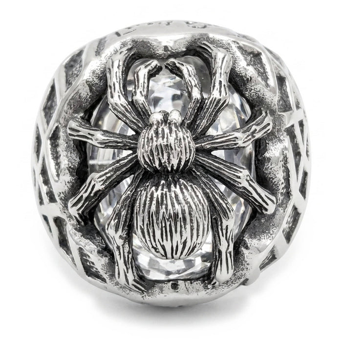 Top-down view of the spider perched over a faceted clear cubic zirconia, legs spread across the silver dome
