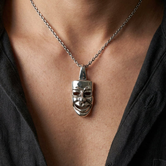 Man wearing silver comedy theater mask pendant on a chain
