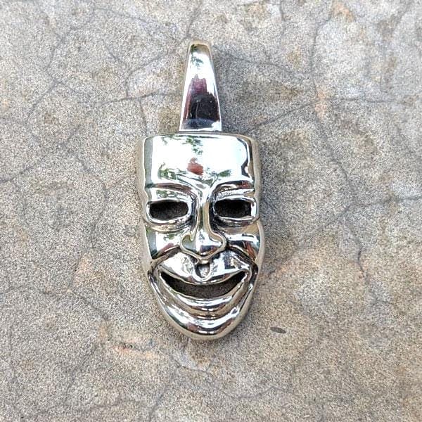 Close-up of handcrafted sterling silver comedy mask pendant smiling face
