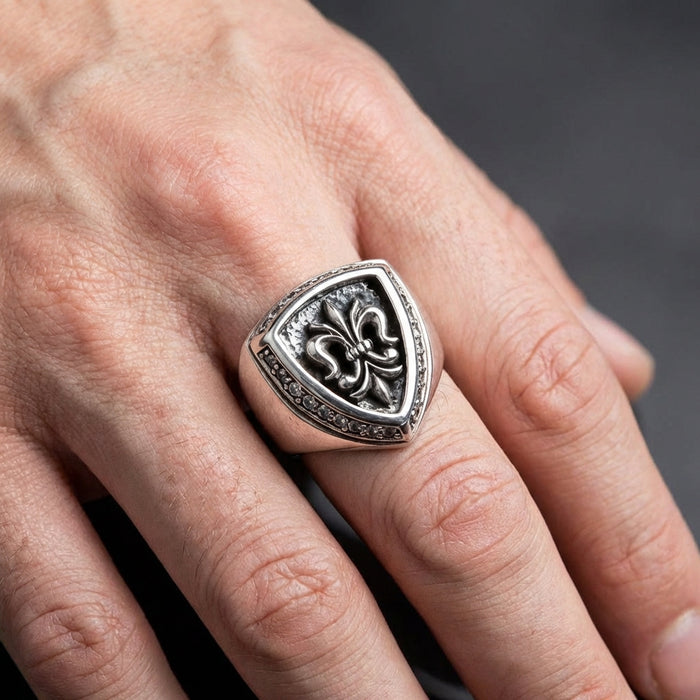 A man's hand wearing the substantial sterling silver fleur de lis ring to show scale and fit.