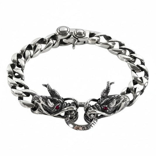 A men's solid sterling silver dragon bracelet with a 12mm Cuban link chain and double dragon head centerpiece with garnet eyes.