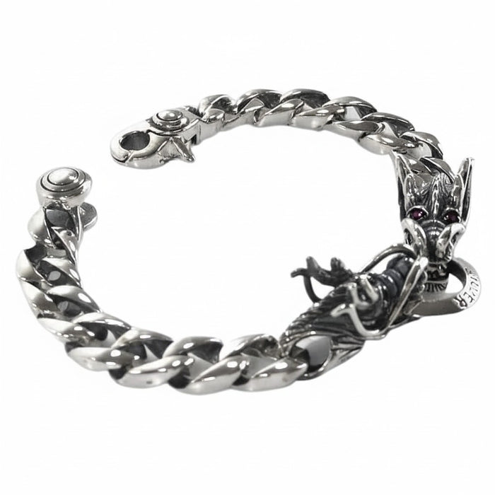 Close-up of the double dragon head design on the sterling silver bracelet, showing sculpted scales and garnet eyes.