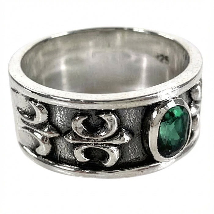 Side view of silver band featuring Fleur de Lis carving and green CZ