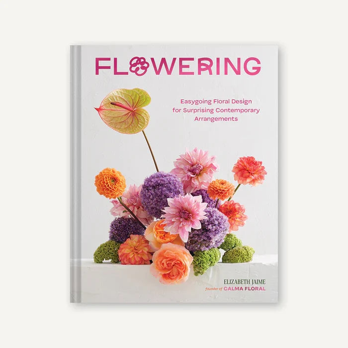 A book cover of 'Flowering' featuring a vibrant arrangement of multicolored flowers with a pink and purple emphasis, designed by Calma Floral.