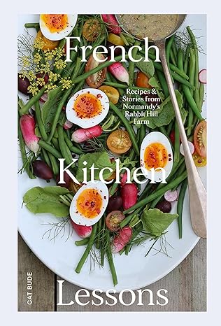 The cover of the book 'French Kitchen Lessons' featuring a vibrant image of a French kitchen setup with various fresh ingredients such as eggs, vegetables, and fruits, alongside a wooden cutting board.