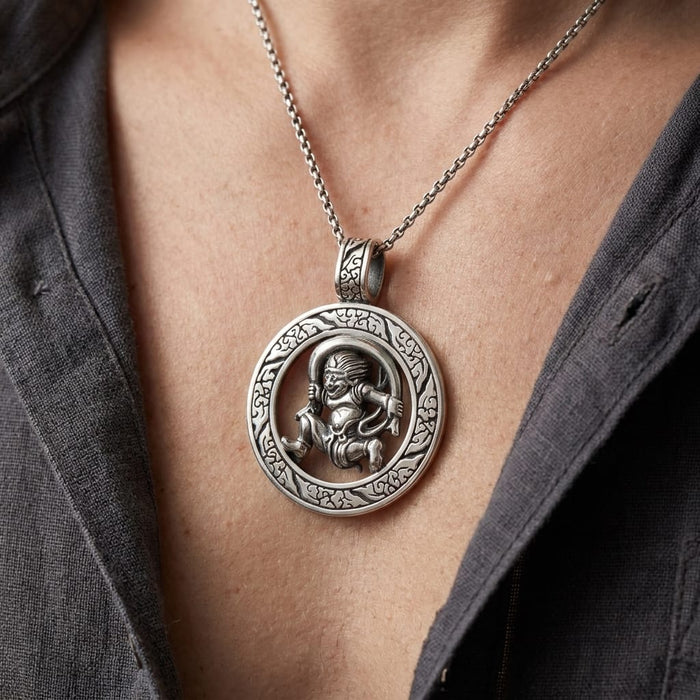 Close-up lifestyle shot of a man wearing a detailed silver Japanese Fujin pendant necklace. The circular pendant features the mythical wind god with intricate border patterns, resting on his chest framed by an open grey button-down shirt.