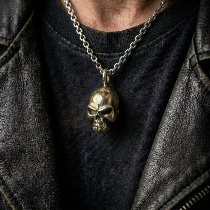 Lifestyle shot of the split-metal skull pendant worn on a silver chain over a black t-shirt and leather jacket.