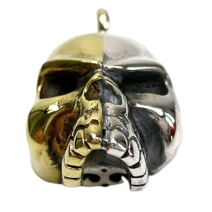Close-up showing the hard line bisecting the skull pendant into high-polished gold brass and mirror-bright sterling silver.
