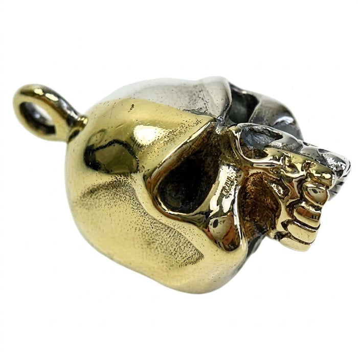 Angled side profile of the split-metal skull pendant highlighting the high-polished gold brass half and top bail loop.