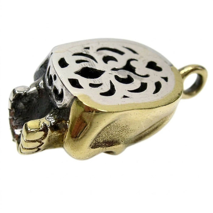 Hollow back of the two-tone skull pendant showing patterned silver cutouts contrasting with the smooth gold brass side.