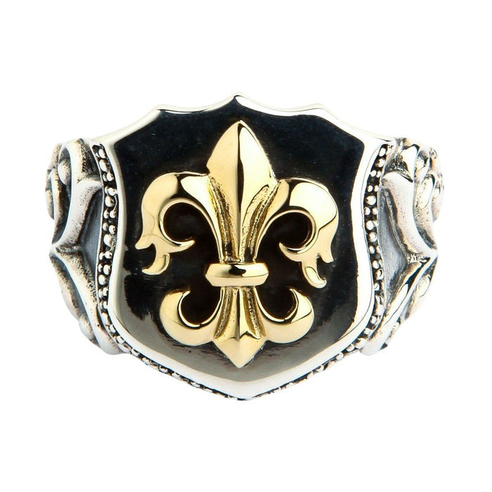 Close-up of shield-shaped ring face featuring a raised gold fleur de lis emblem against a dark oxidized sterling silver background with beaded border