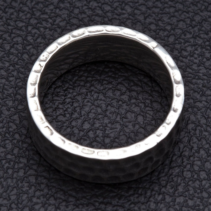 A solid, hand-forged style silver ring with a unique, character-rich, and textured surface.
