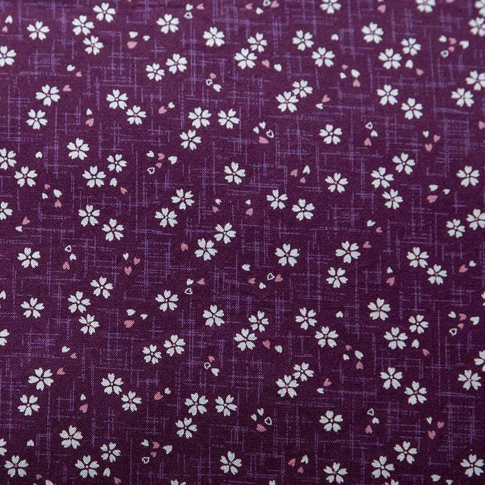 Close-up view of purple fabric with a Sakura pattern featuring white and pink flowers.