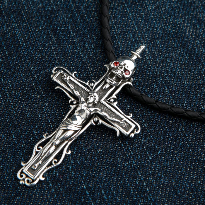 Resting on blue denim, the silver crucifix displays the figure of Jesus below a dagger-pierced skull with red garnet eyes.
