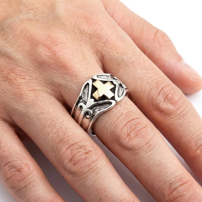 Close-up of a male model's hand wearing a chunky silver biker ring featuring a prominent gold Knights Templar cross and oxidized gothic detailing, set against a plain white background.
