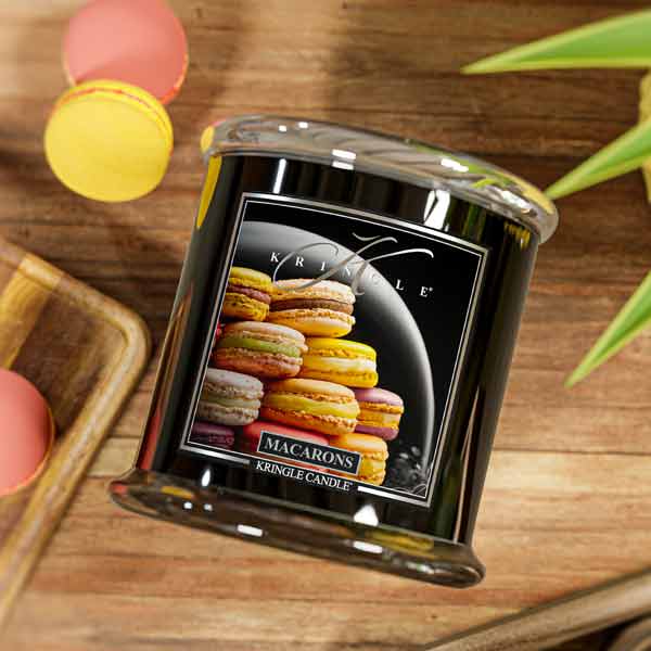 Kringle Candle macaron scented candle on a wooden surface with colorful macarons in the background.