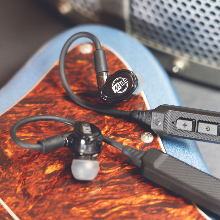Black MEE audio MX2 PRO Musicians' In-Ear Monitors and BT3 Hi-Res Bluetooth Audio Adapter displayed on a guitar.