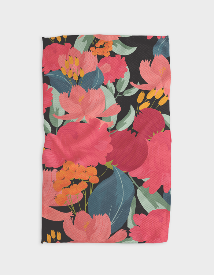 A tea towel with a floral print featuring pink and green flowers on a black background, and a dark loop for hanging.