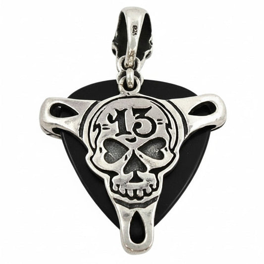 A sterling silver guitar pick holder pendant featuring a number 13 skull design, shown holding a black pick.