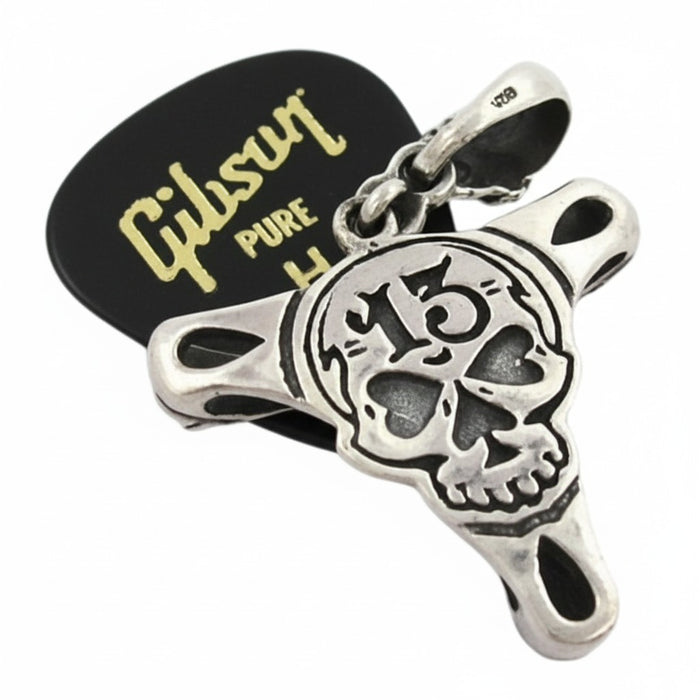 An angled view of the gothic guitar pick necklace, showing the detailed skull and claw grips.