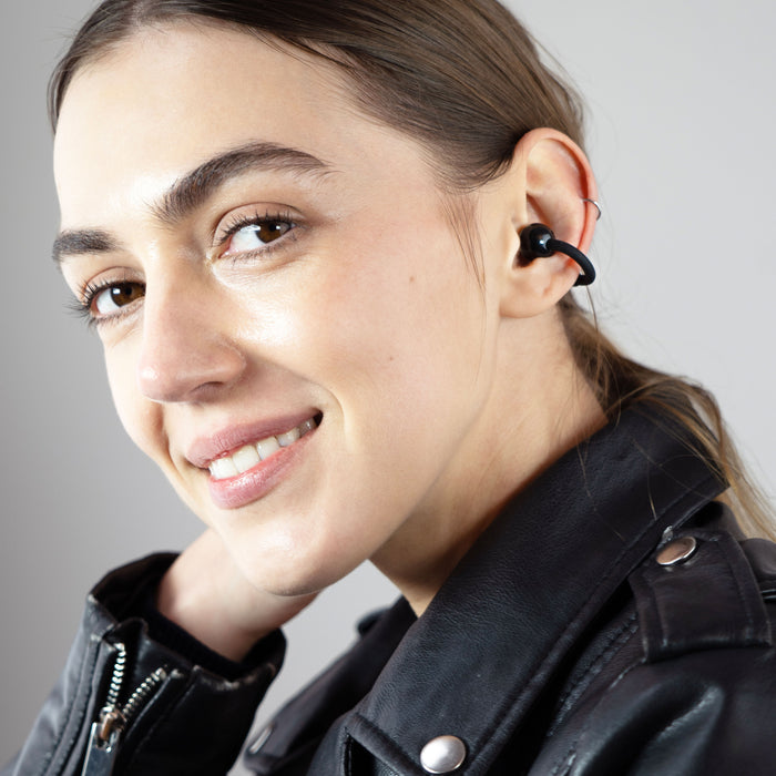 A woman wearing the onxy Pebbles Air earbuds while smiling.
