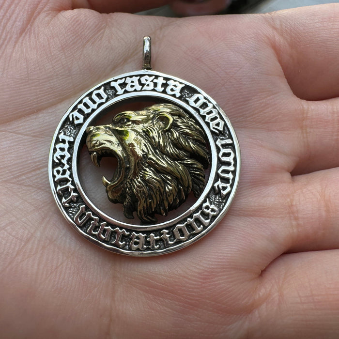 Top-down palm view of the Rasta Lion medallion showing the full engraved gothic script border around the brass lion