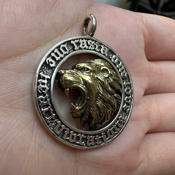 Angled palm shot of the 40mm Rasta Lion coin pendant showing the raised gothic lettering on the silver frame
