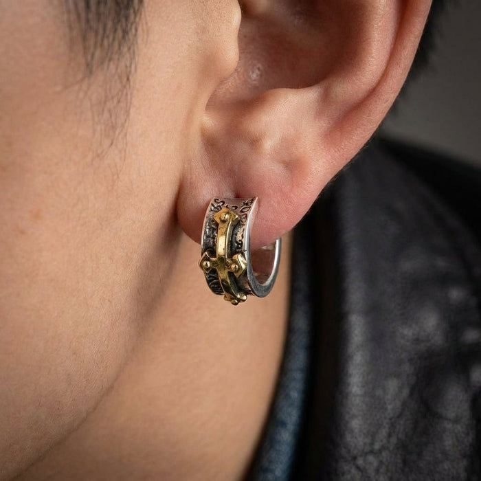 Man wearing sterling silver cross hoop earring with gold accent paired with black leather jacket
