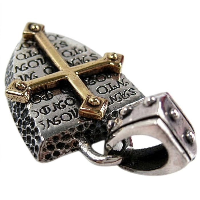 Low angle focusing on the studded silver bail and thick hammered edges, with the brass cross visible above.