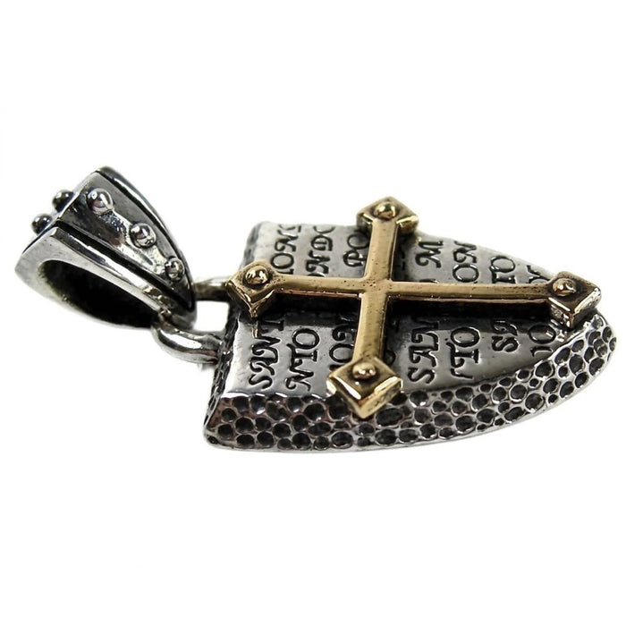 Side profile of the two-tone pendant revealing the thick, dimpled silver edge and the raised brass cross over engraved text.