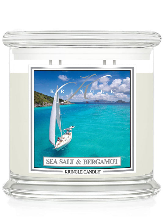 Clear glass candle labeled "Sea Salt & Bergamot" depicting a sailboat on turquoise water under a blue sky.