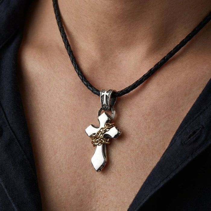 Sterling silver cross pendant with yellow gold chain worn on neck with braided leather necklace