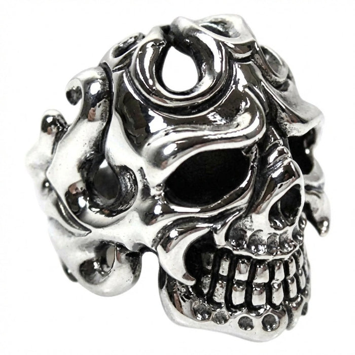 Sterling silver tribal skull ring photographed from right side angle showing flame pattern details and teeth
