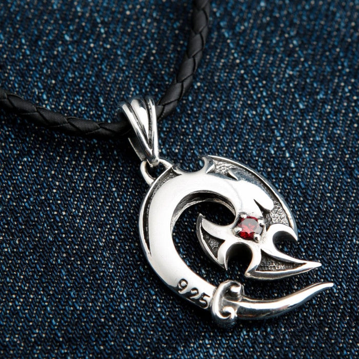 Sterling silver tribal hook pendant with red garnet stone close-up on denim background