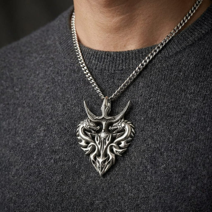 Close-up of a man wearing an intricate silver twin guardian dragon pendant necklace featuring a small center diamond, styled over a dark grey knit sweater.