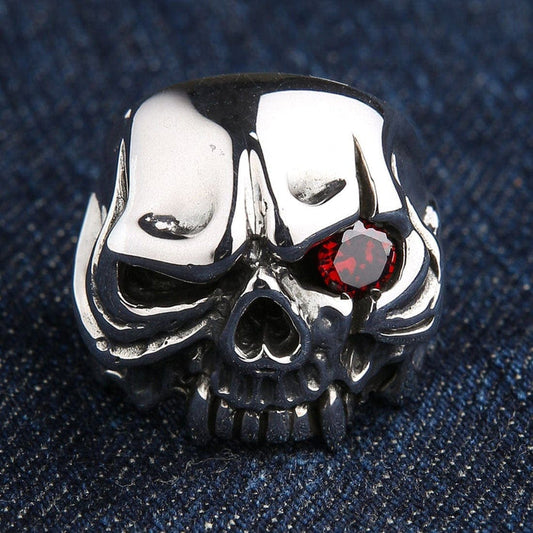 A front view of the men's sterling silver vampire skull ring with a single red CZ eye, resting on a denim background.