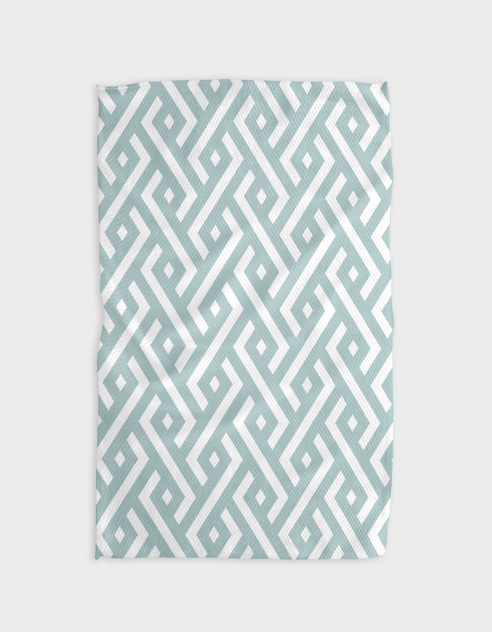 A kitchen tea towel with a geometric pattern in blue and white colors, featuring a hang loop on one corner.